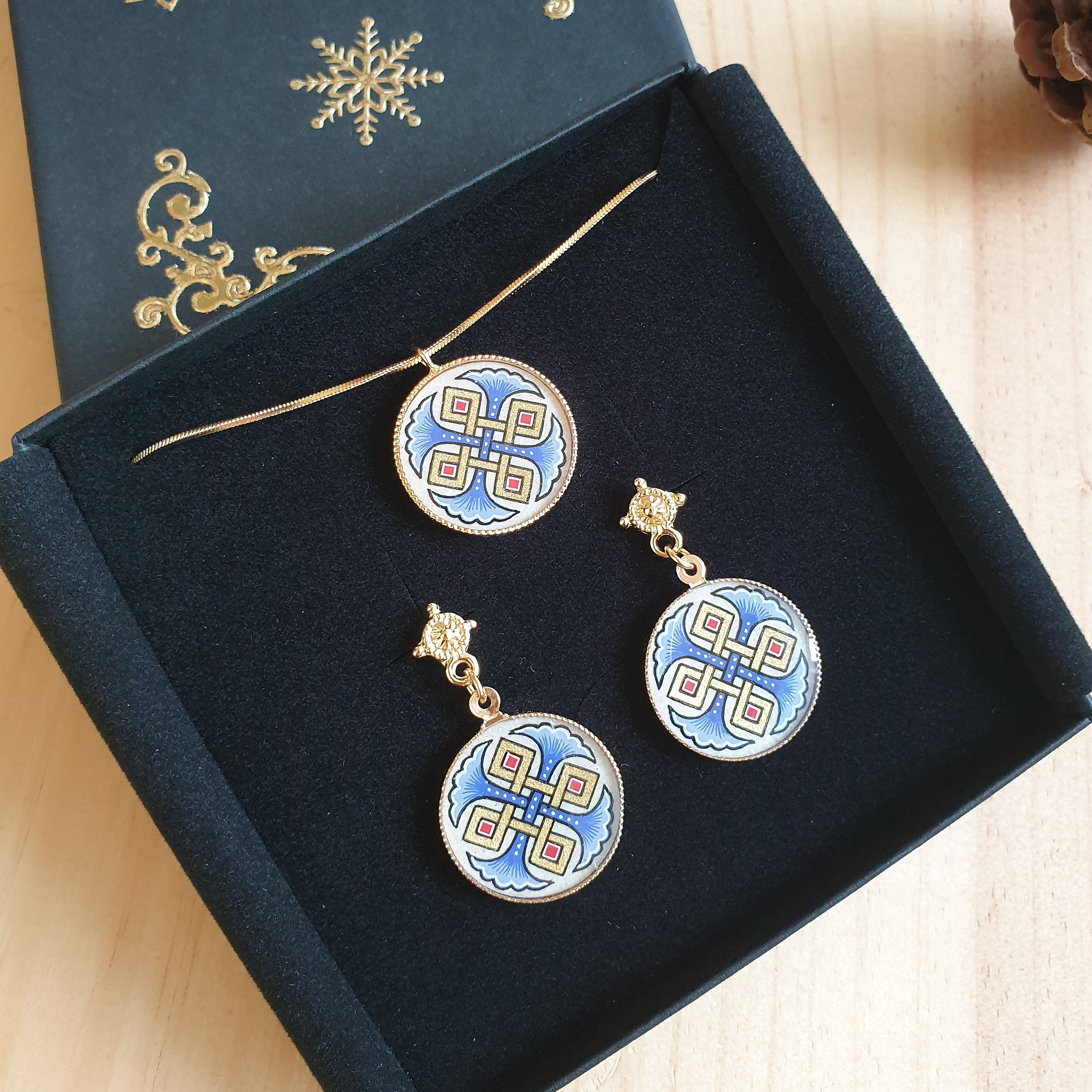 Orecchini illuminati con palmette rosse o blu e intrecci dorati