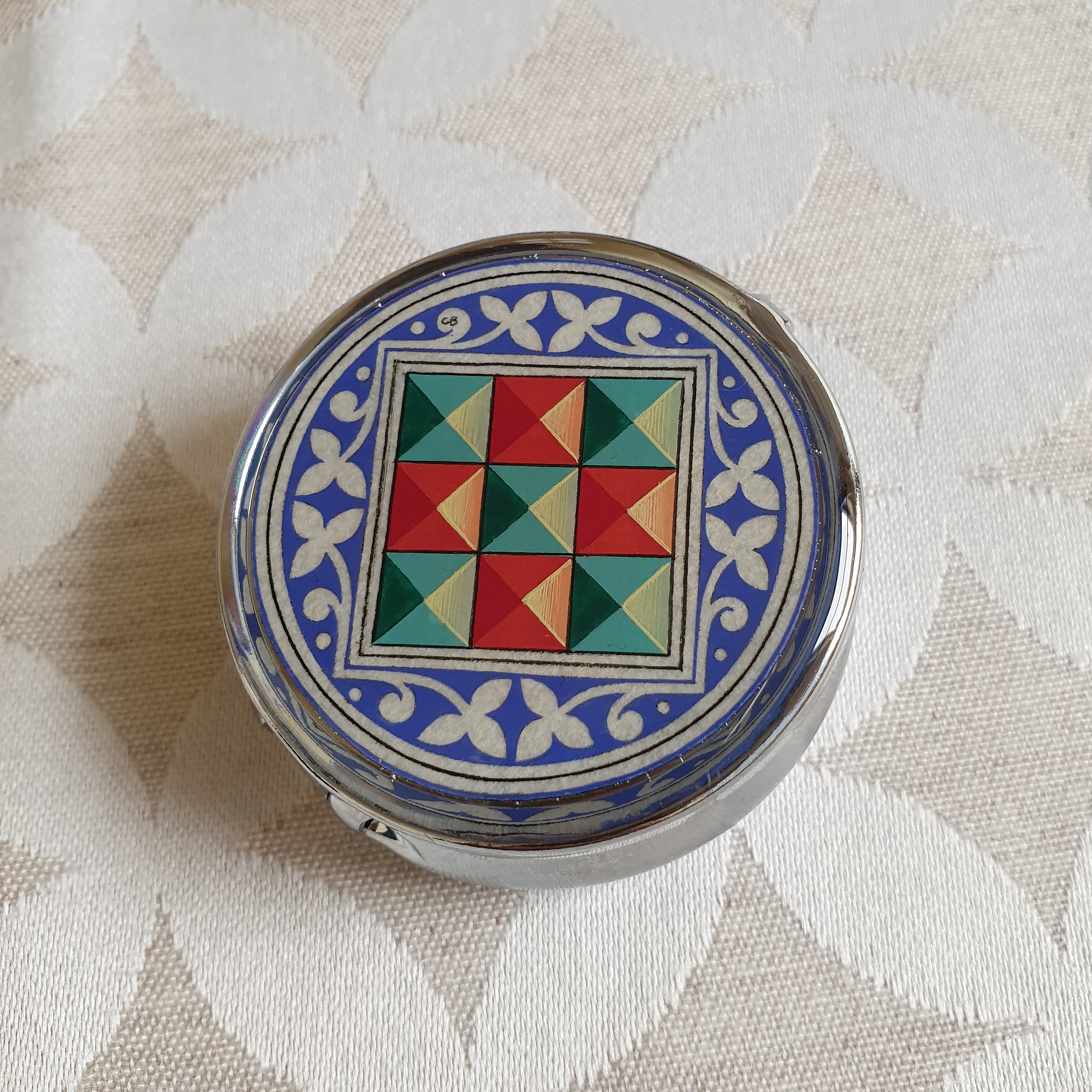 Petit pilulier métallique avec enluminure florentine colorée.